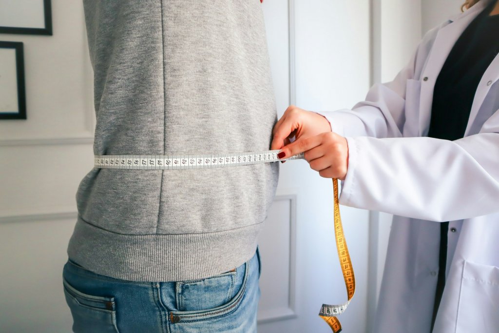 a woman measuring her waist with a measuring tape