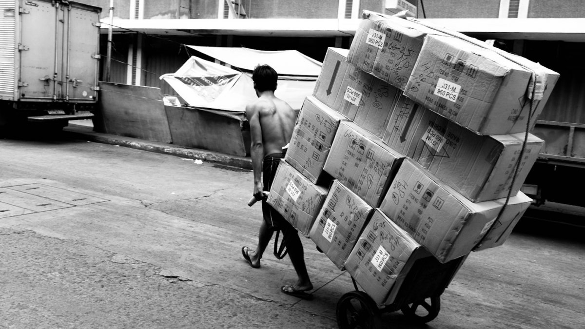 a man pushing a cart full of boxes down a street