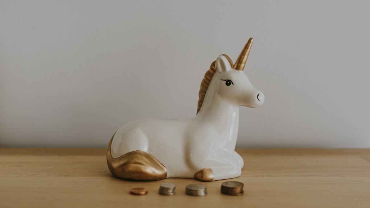 white and gold ceramic unicorn figurine near coins