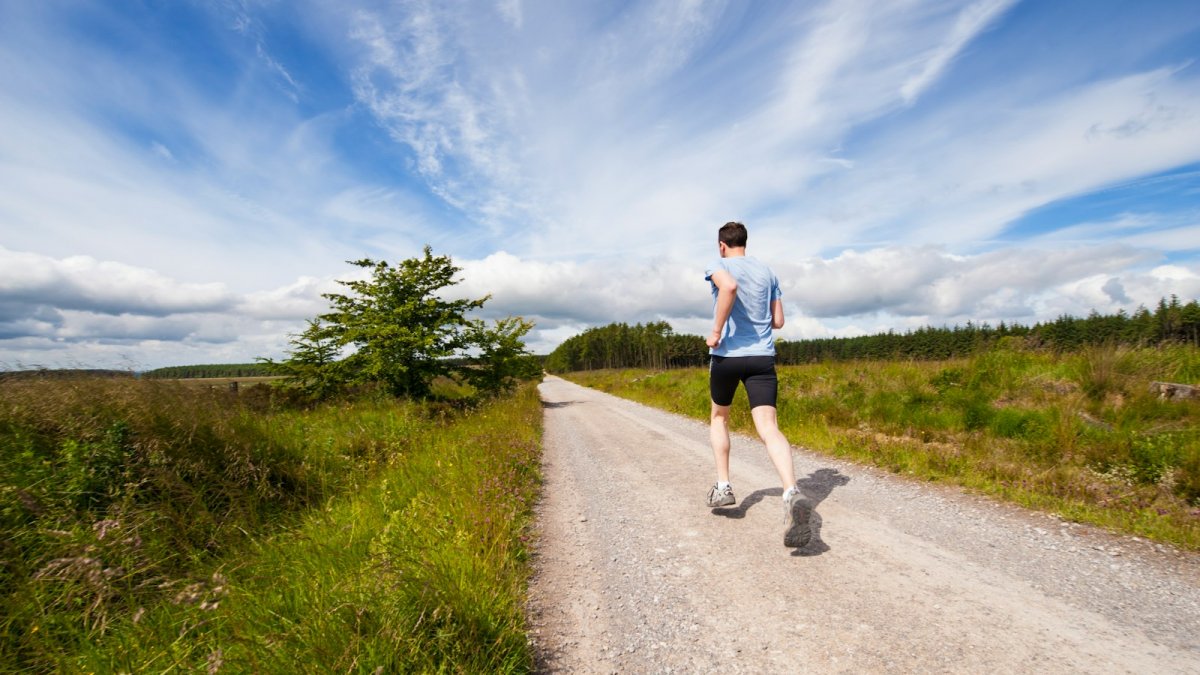man running on road near grass field